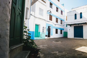 Fototapeta na wymiar Sunny street with traditional white building in the town of Asilah, Morocco