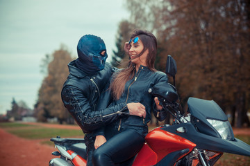 Obraz premium portrait of a beautiful hipster girl on a sports motorcycle with a guy in the skull mask