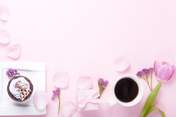 Chocolate cupcake with icing, coffee in a white cup on a pink gentle background	