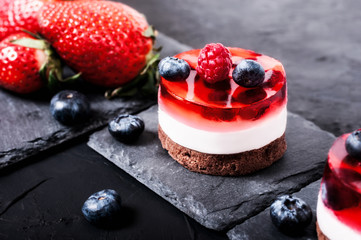Cake with jelly, blueberries, raspberries and strawberries on a black background	