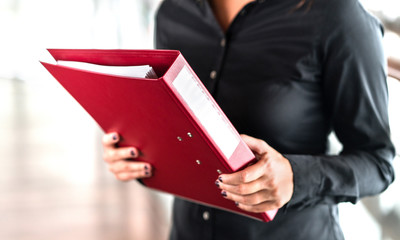 Professional business woman holding folder full of paper documents. Lawyer, legal adviser, office assistant or company manager with binder.