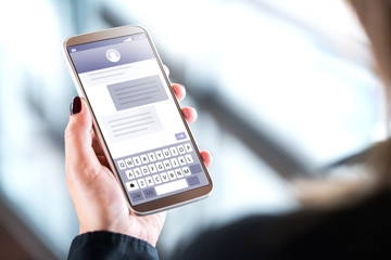 Woman sending text messages with mobile phone. Cellphone in hand with sms application on screen....
