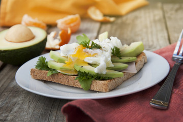 Bread toasts with avocado, eggs and greens. Tasty breakfast. Wood background. Isoalted.