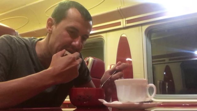 man at night eating soup in the train restaurant railway cat drinks coffee. man on lifestyle the train concept journey travel railway