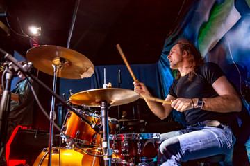 Drummer playing on drum set on stage.