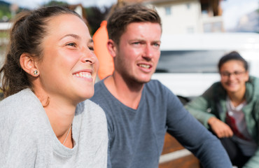 Fototapeta premium several young male and female people sitting on a bench and smiling and watching a game