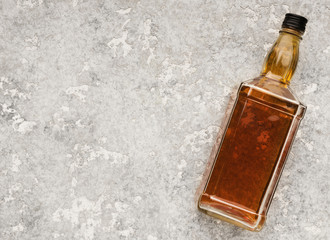Blank bottle with whiskey or cognac on stone background