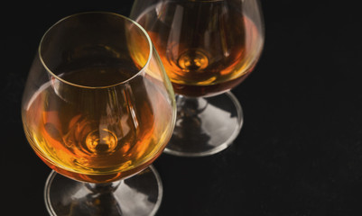 Cognac portions in glass on black background