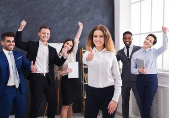 Happy businesswoman showing thumb up in office