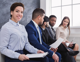 Cheerful woman sitting in queue while waiting interview