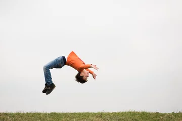 Foto op Plexiglas healthy sport little boy jumping somersault outdoors nature with copyspace © ruslanshug