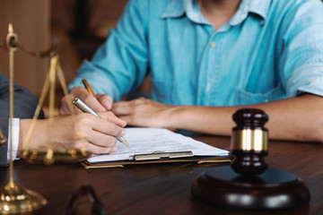 Judge gavel with Justice lawyers having team meeting at law firm in background. Notary with client in office