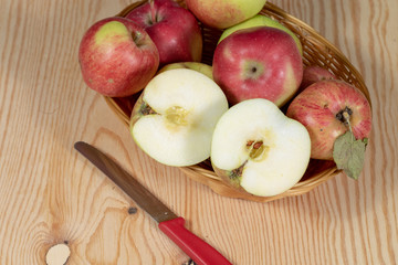 Halved apple in a basket with some other ripe apples