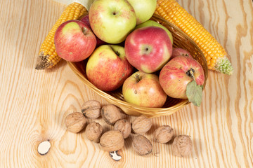 Naklejka na ściany i meble Basket full of apples beside walnuts and corn combs