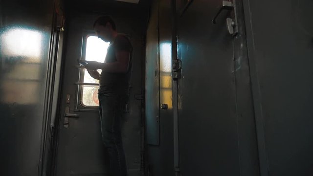 the man silhouette is standing on the train Railway carriage holding a smartphone and . slow motion video. man writes messages in the smartphone in the train social media. man with smartphones train