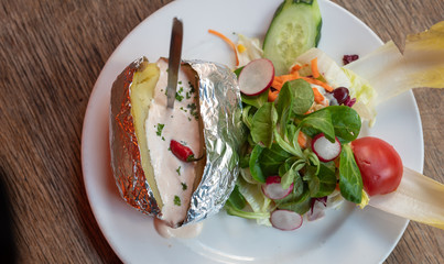 Ofenfolienkartoffel mit Sour Cream Joghurt und Beilagen Salat in einem mexikanischem Restaurant