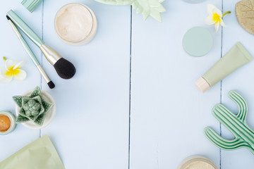 Beauty background with facial cosmetic products with succulents and make up brushes on blue wooden background flat lay frame