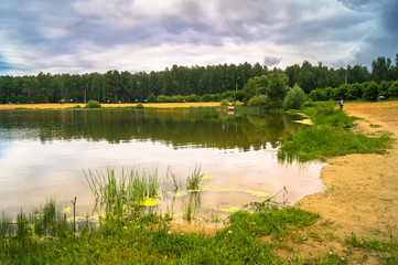 Natural forest lake with artificial sandy beach for free public leisure activities. Moscow residential suburb, Zarya district, Balashikha. Russia.