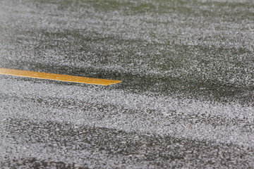 Wet rain on asphalt road with yellow line.