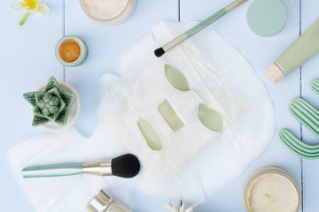 Beauty background with facial cosmetic products and sheet mask on blue wooden background. Beauty spa and wellness concept.