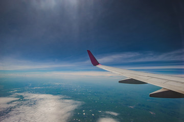 Fototapeta premium Looking through window aircraft during flight in wing with a blue sky
