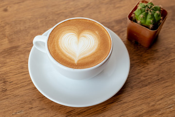 Coffee latte art flower shape in a white cup on wood table on relax time