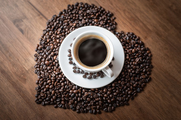 Hot coffee cup with heart pattern of roasted coffee beans