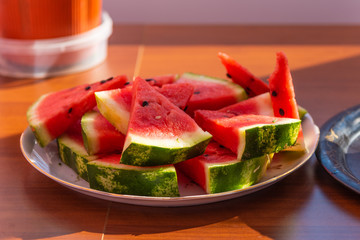 Ripe red sliced watermelon on a plate on a table