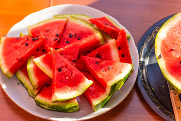 Ripe red sliced watermelon on a plate on a table
