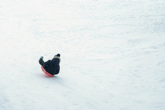 Small child riding on sledge from snowy hill