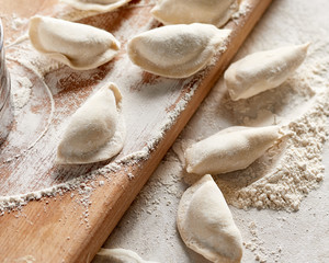 Raw russian dumplings with flour on table