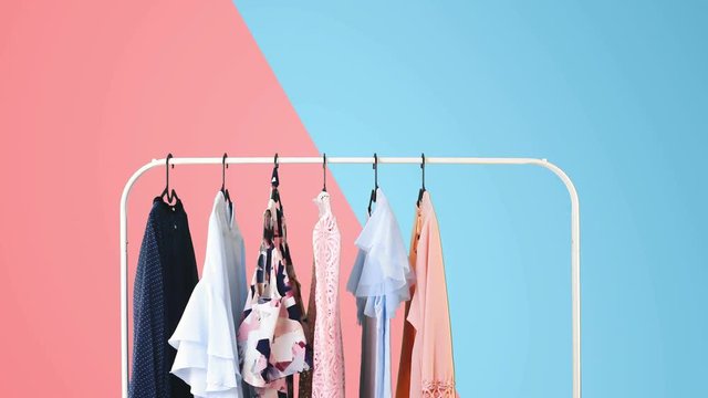 Women's clothing on a white clothes hanger on pink and blue pastel colors background.