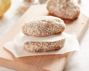 Raw chicken cutlets on wooden cutting board
