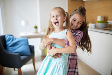 Two little adorable girls in dresses having fun in the kitchen and playing with each other