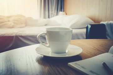 Coffee cup on wooden table morning time coffee in the bed room for wake up life- warm vintage tone
