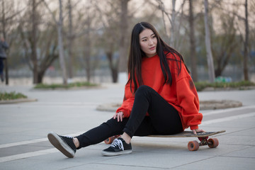 Young woman sitting on her skateboard © ddukang