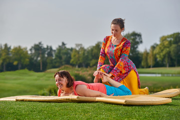 Thai therapy outdoor. Mature woman getting traditional thai stretching massage by therapist in the park.