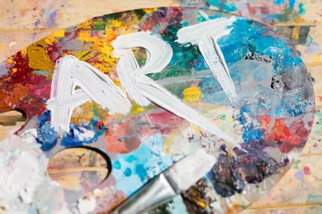 Poster Word art painted with white gouache on colorful palette with paintbrush near by © pressmaster