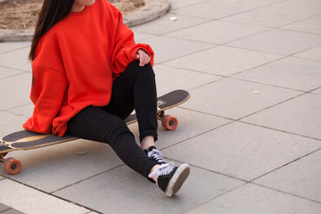 Young woman sitting on her skateboard