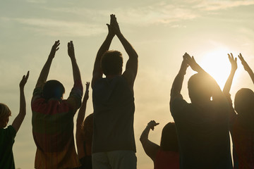 Applauding people silhouette. Rear back view handclapping family against morning sunrise.