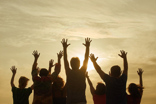 Teenage people having fun outdoor. Raising hands up while morning sunrise.