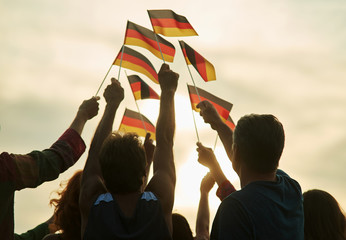 German patriots with flags. Silhouette. Evening sky background.