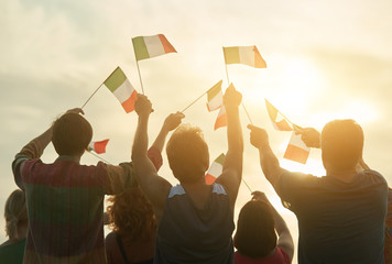 Raising italian flags. Patriotic people raising flags to the evening sky, back view.