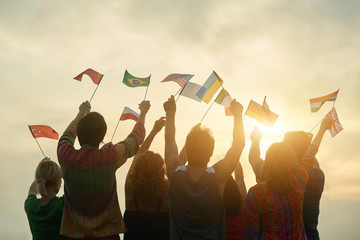 Countries friendship concept. Crowd of people with flags, back rear view. Sunny sky background.