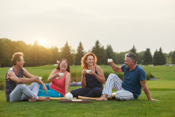Fototapeta premium Happy people laughing. Tea party conversation outdoor in the summer park.