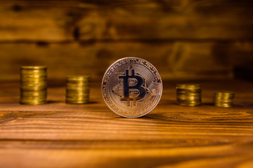 Bitcoin and stack of coins on wooden table