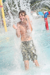 Smiling boy getting splashed at a waterpark