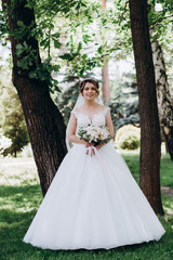 A bride in a white dress is holding a beautiful wedding bouquet.