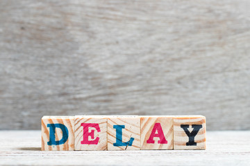Letter block in word delay on wood background