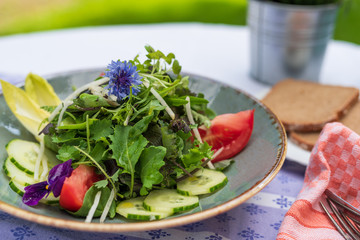 Frischer Markt gemischter Salat mit Blumen und Kräutern im Biergarten serviert